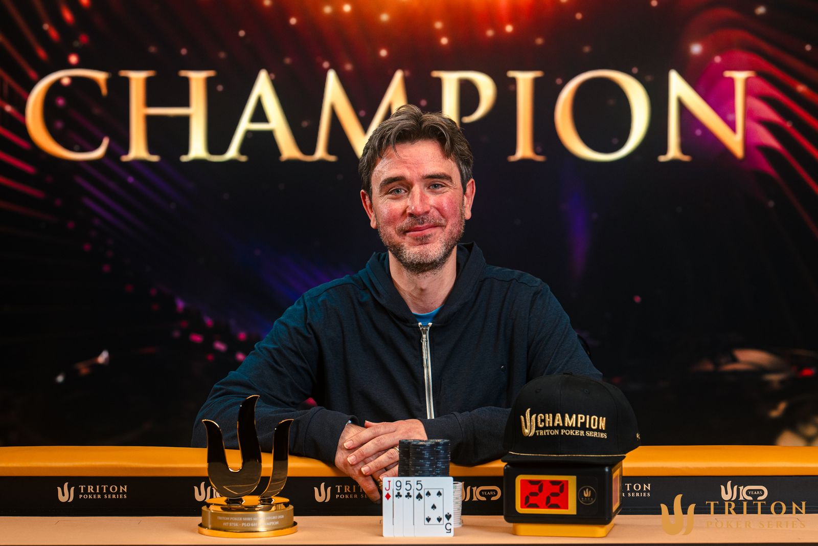 Richard Gryko sosteniendo un trofeo de Triton Poker tras ganar un evento.