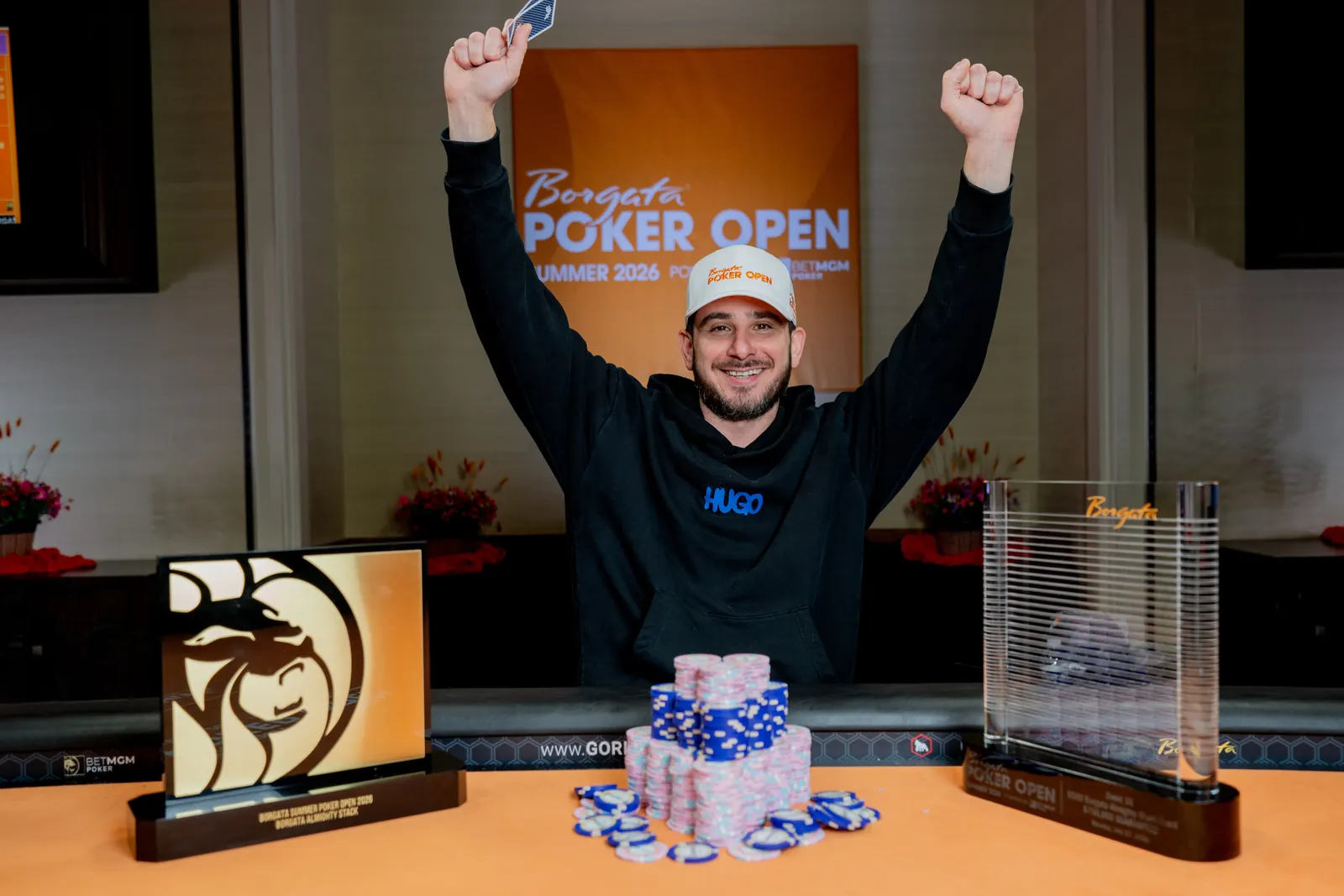 Mesa de poker con fichas y cartas, logo del Borgata, y trofeo del torneo Borgata Almighty Stack
